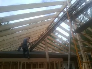 Rafters going up over a new addition with a worker on the wall in Montevideo