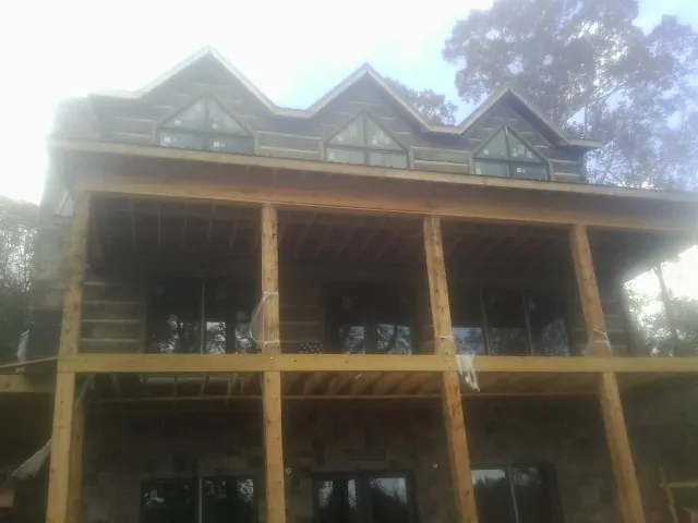 Dormers and porch framing on a large log home under construction — Roof Coating work by our crew in Montevideo