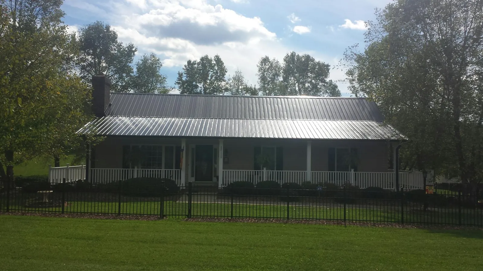 Gray metal roof on a brick ranch with a full width front porch — Gutter Guard Installation work by our crew in Montevideo