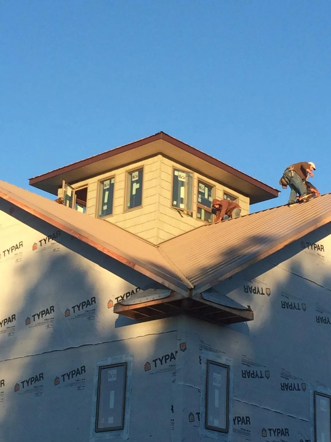 Roofers working around a rooftop cupola on a new metal roof at sunset — Roof Waterproofing in Montevideo by Roofing Brothers